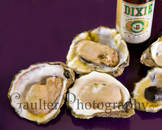 Opened oysters on purple background with a Dixie Beer in the background